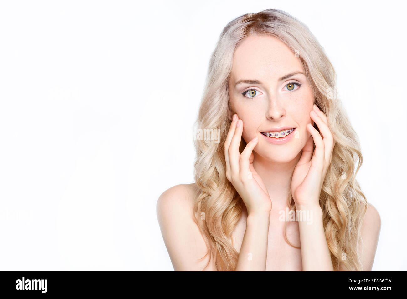 Ritratto di una giovane donna con bretelle toccare leggermente il viso con le mani. Foto Stock