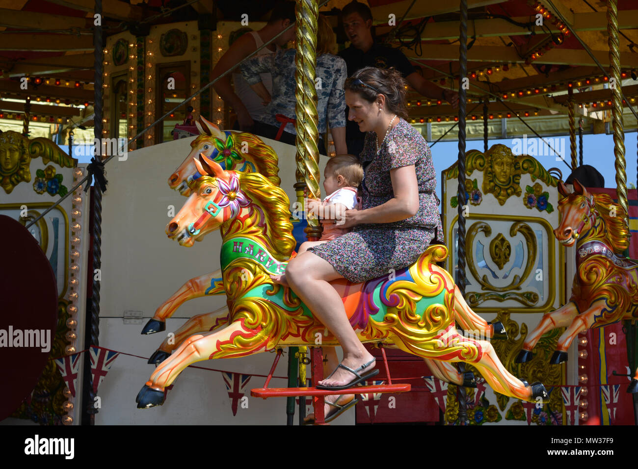 La madre e il bambino a cavallo sulla merry-go-round all'annuale Sherborne Castle Country Fair, Sherborne, Dorset, Inghilterra. Foto Stock