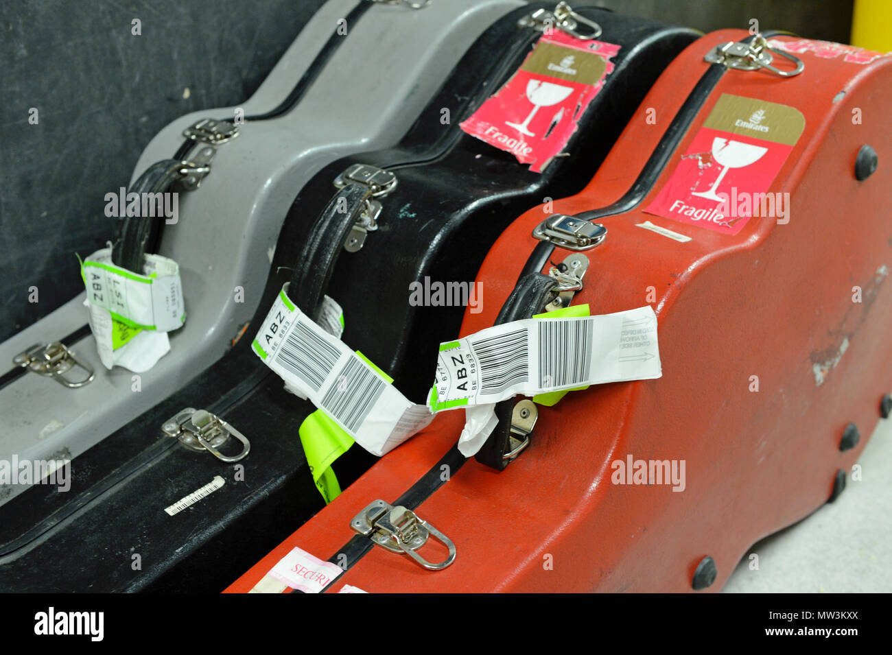 Selezione di diverso colore volo chitarra casi che giace dietro le quinte ad un concerto con carta di imbarco di etichette su di essi Foto Stock Selezione di diverso colore volo chitarra casi che giace dietro le quinte ad un concerto con carta di imbarco di etichette su di essi Foto Stock