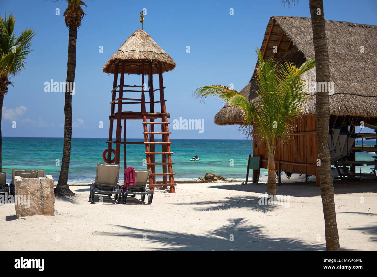 Vista resort hotel di lusso di spiaggia di Costa Tropicale. Luogo di bagnino. Foglie di palme da cocco che fluttua nel vento contro il cielo blu. Acque turchesi del Mar dei Caraibi. Riviera Maya Messico Foto Stock
