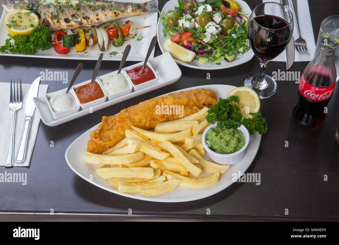 Pesce e patatine, una tradizionale britannico popolare della pietanza servita con ketchup e tartare di salsa. Frittura di pesce martoriato e hot potato chips, un popolare da asporto. Foto Stock