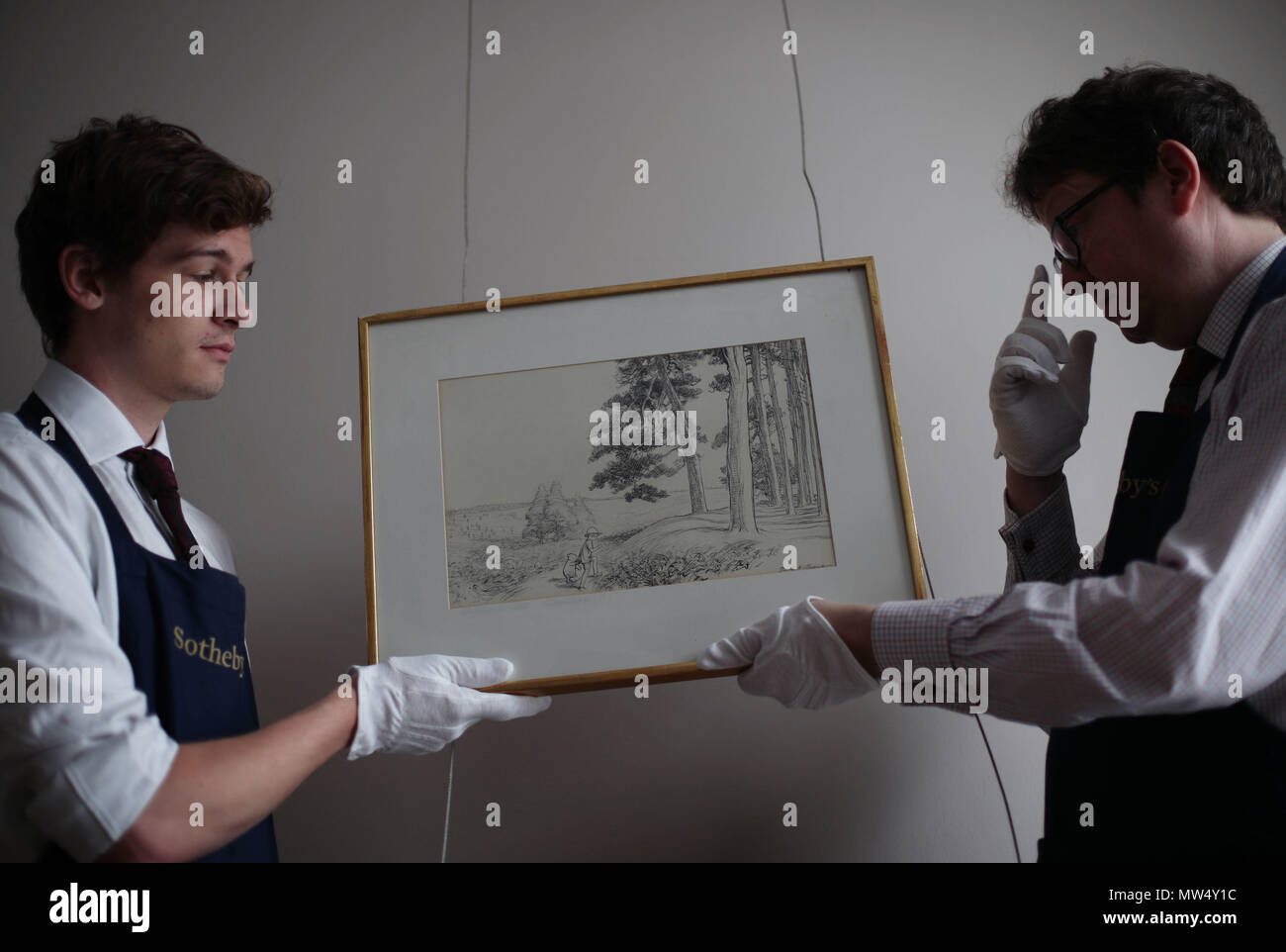 I tecnici di Sotheby che gestiscono un disegno originale firmato di inchiostro da E.H. Shepard of '...un posto incantato sulla cima della foresta', 1928, stima £70,000-£90,000, durante la presentazione della mappa originale di Winnie-the-Pooh's Hundred acri Wood di e H Shepard presso la saleroom di Sotheby nel centro di Londra in vista della sua vendita presso la casa d'aste. Foto Stock