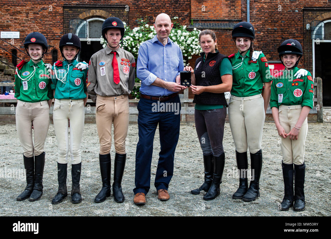 (Da sinistra a destra) Maia Davies, Lola Doyle, Matthew Sheppard, Stephen Lee, Managing Director di Bradford Exchange, Theresa Barrett, direttore stabile del cavallo Associazione Rangers, Caitlin Aldous e Abi Evans pone durante il lancio dell'oro quarto sovrano di includono il ritratto della regina a cavallo rilasciato da Bradford Exchange presso il cavallo Rangers Association, Royal Mews, Surrey. Foto Stock