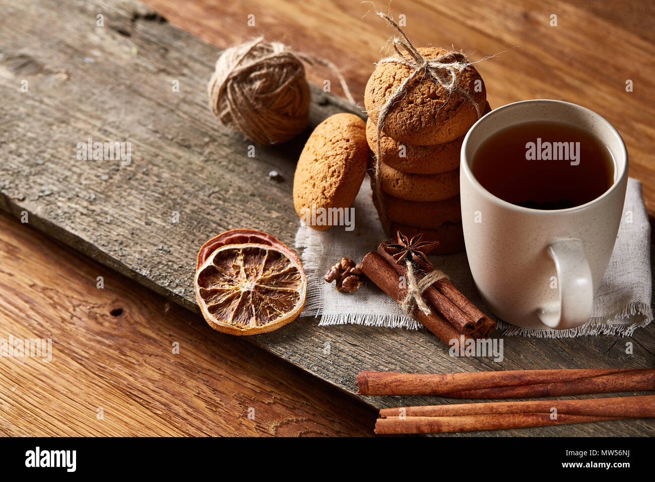 Natale tradizionale concetto di tè con una tazza di tè caldo, una grande serie di cookies su un tovagliolo homespun, bastoncini di cannella mazzetto, un paio di arance essiccate Foto Stock