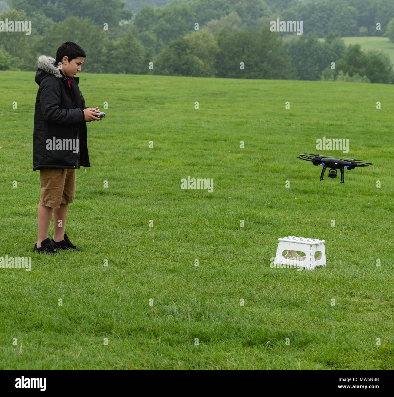 Biracial boy vola drone a Weald Country Park modello di rilascio trattenuto Foto Stock