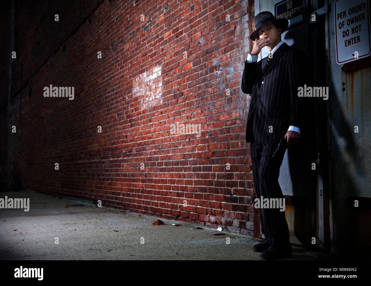 Un 1940s gangster stile di vedetta in un vicolo buio Foto Stock