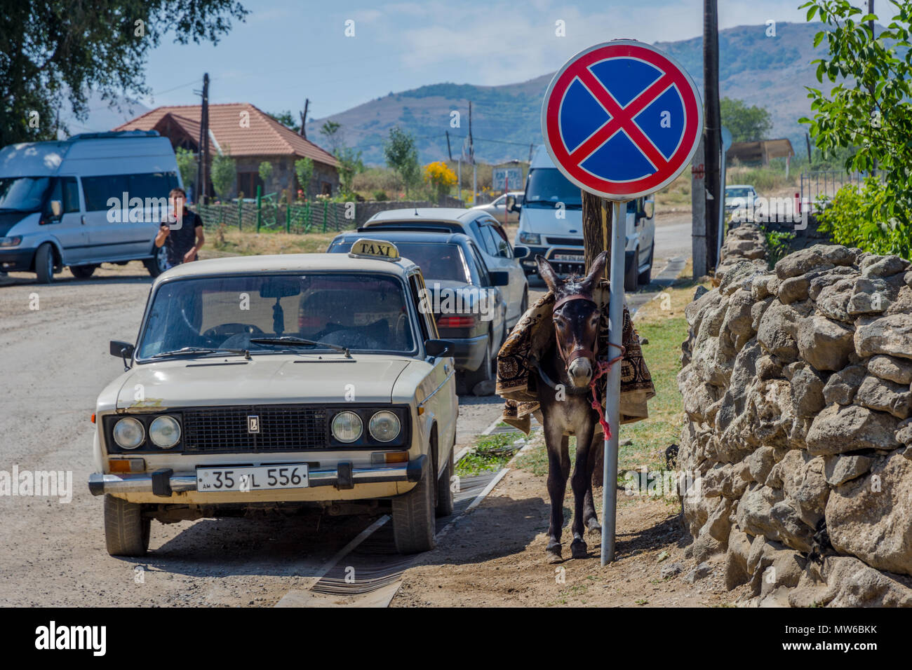 Tatev, Armenia - 9 Agosto 2017: Asino in attesa accanto al vecchio stile taxi Lada al monastero di Tatev, Armenia Foto Stock