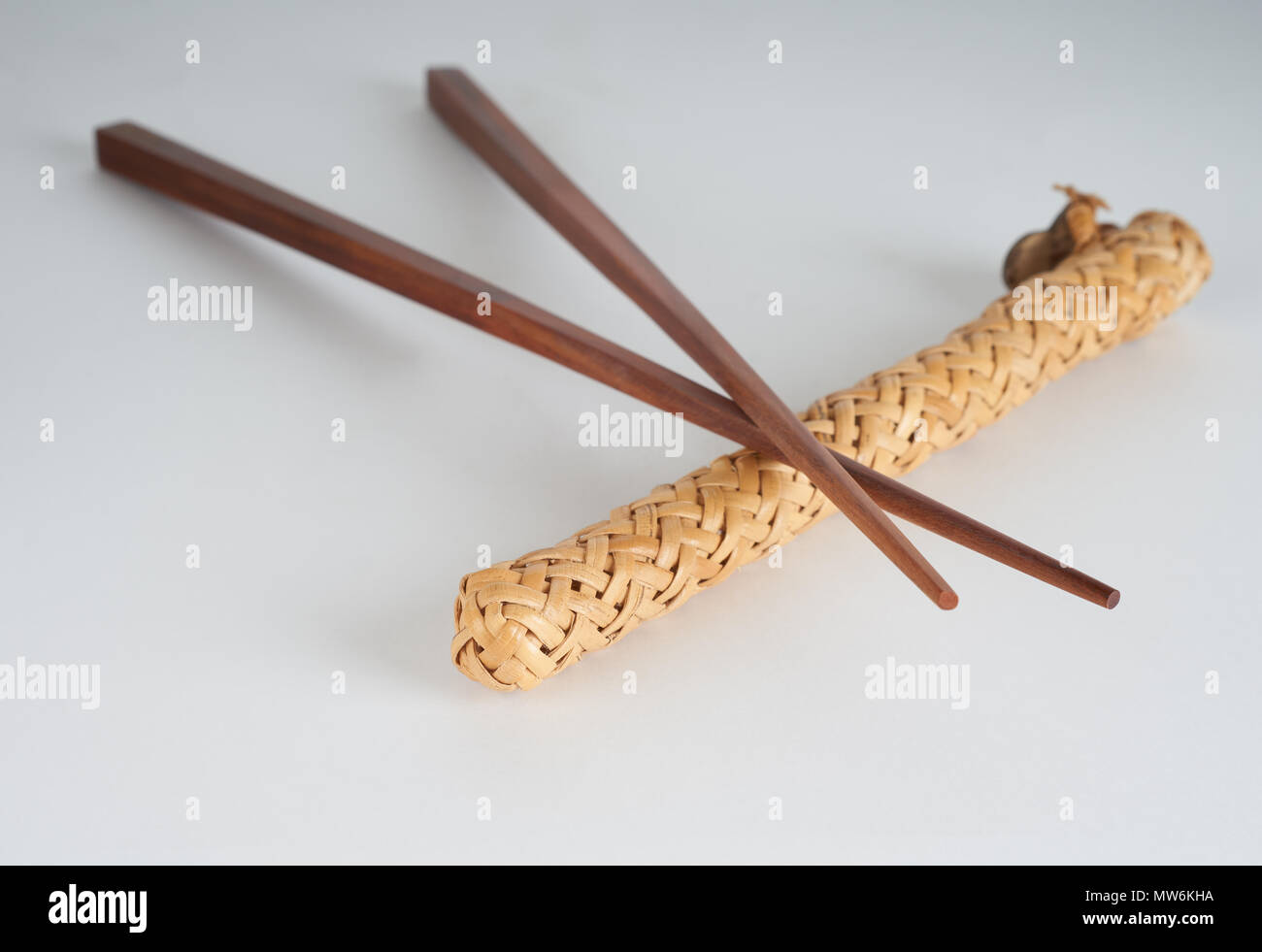 Due tradizionali bacchette di legno sul caso di vimini su sfondo bianco Foto Stock