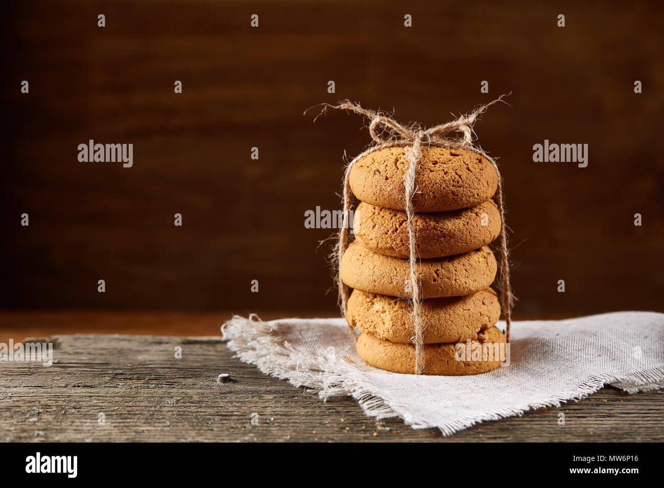 Biscotti fatti in casa tighted con un pezzo di corda sul tovagliolo homespun su un tavolo di legno, close-up, il fuoco selettivo. Pila di deliziosi biscotti. Natale Foto Stock