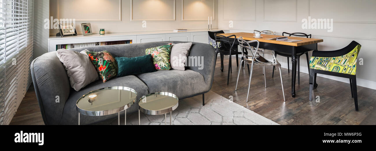 Soggiorno con divano grigio, pareti beige e tavolo, panorama Foto Stock