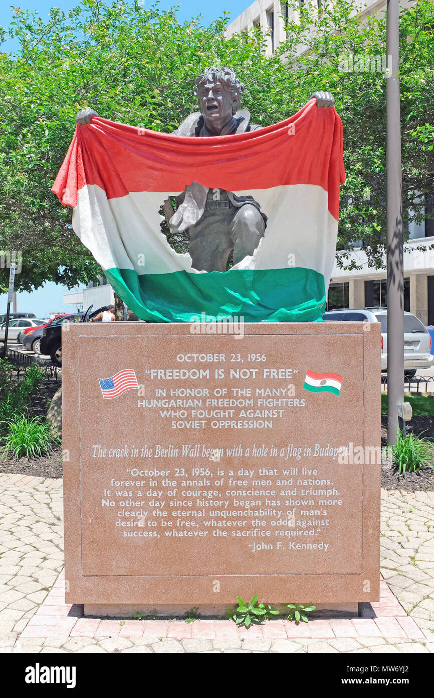 Ungherese Freedom Fighter detiene bandiera ungherese con simbolo comunista ritagliato in Cleveland , Ohio statua simboleggiante il 1956 insurrezione ungherese. Foto Stock
