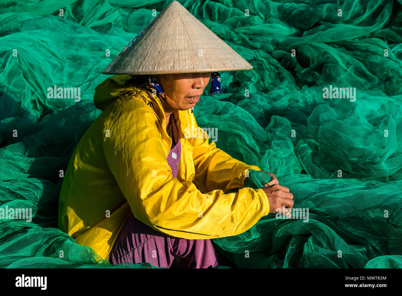 Donna tessitura di reti da pesca al di fuori della sua casa nel Mui Ne, Vietnam Foto Stock