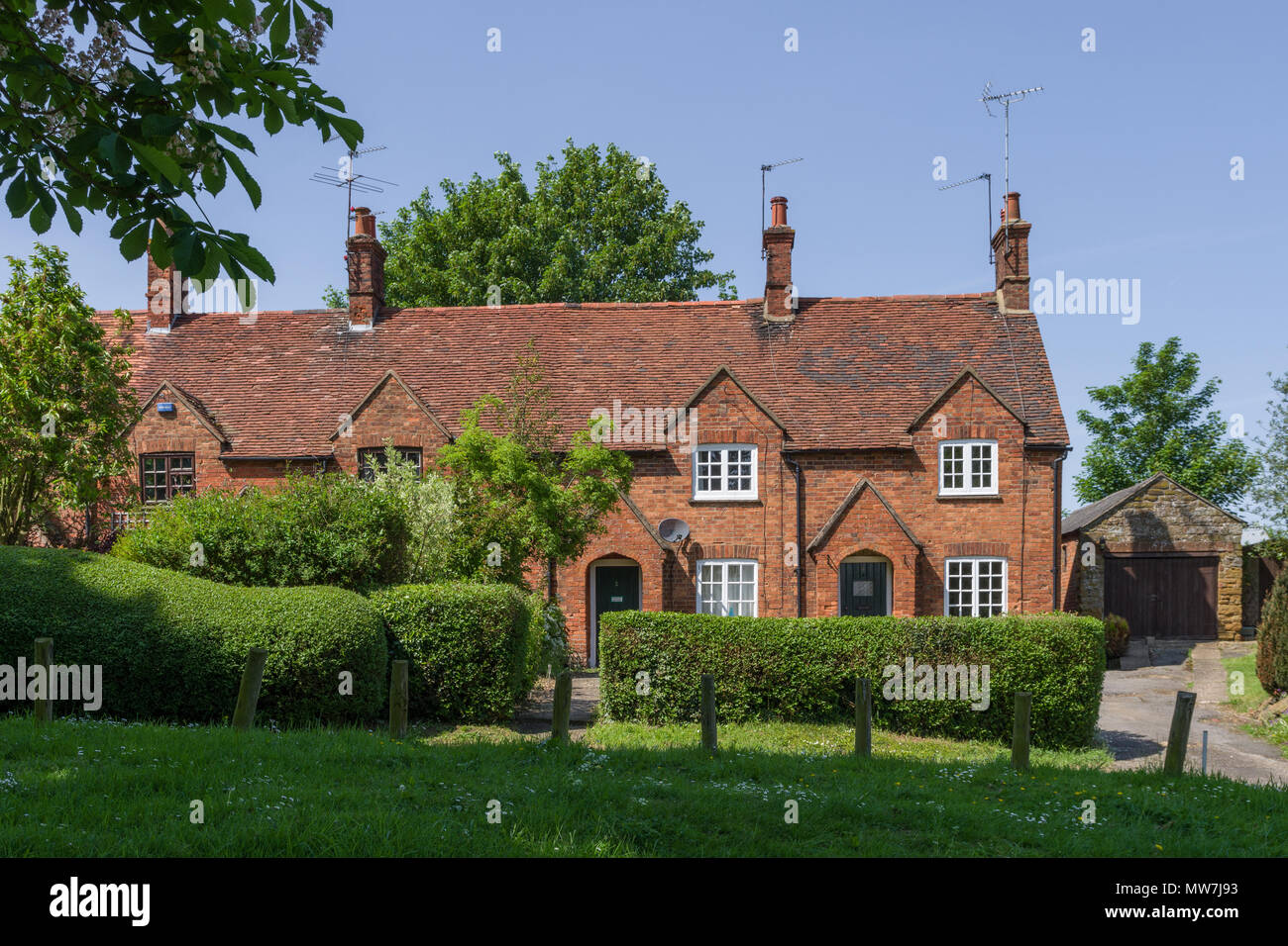 Terrazza di mattoni vecchi cottage costruito che si affaccia sul verde villaggio, grande Brington, Northamptonshire, Regno Unito Foto Stock