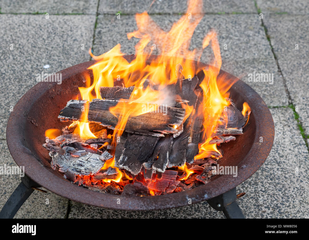 La combustione del legno luminosamente in un metallo una buca per il fuoco Foto Stock