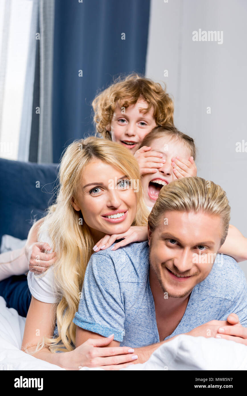 Felice giovane famiglia con due bambini sorridenti in telecamera Foto Stock