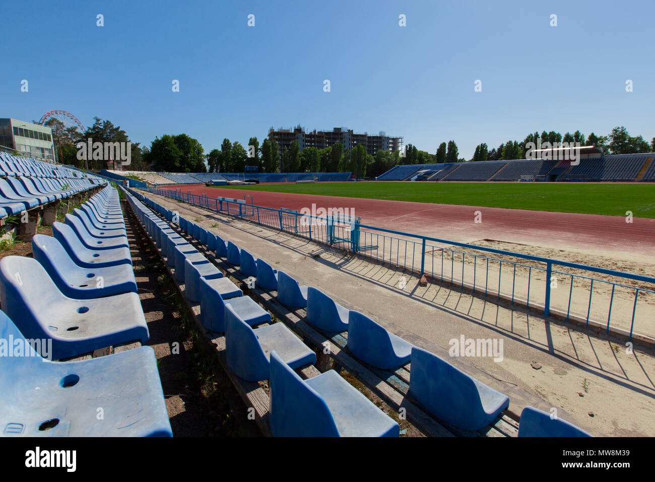 Luminosa giornata di sole blu chiaro cielo blu posto a sedere nello stadio di erba campo verde e traccia in esecuzione Foto Stock