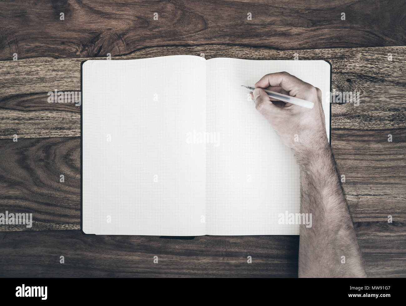 Vista superiore dell'uomo tenendo la penna per scrivere nel diario o Blocco note sul tavolo di legno Foto Stock