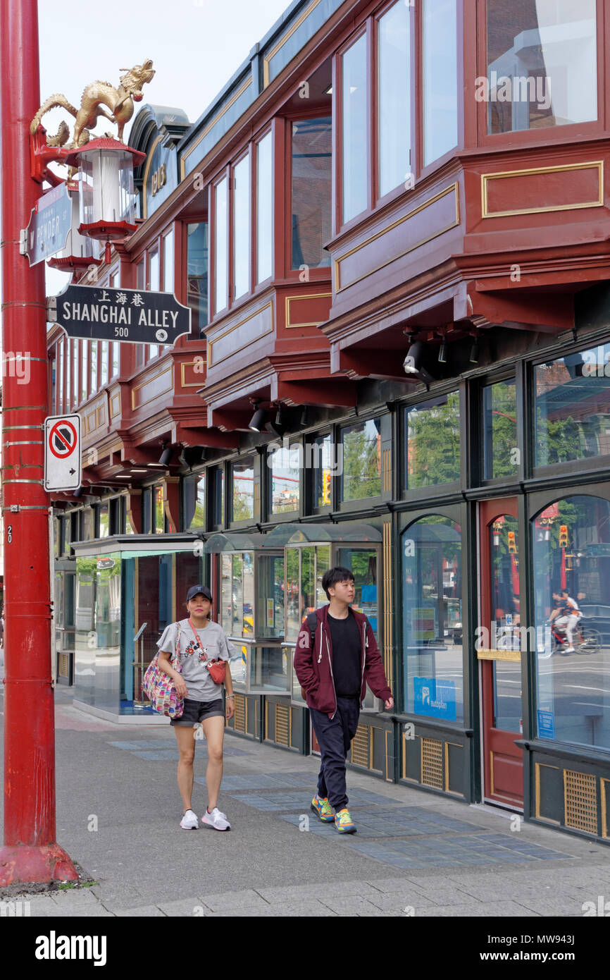 Giovani asiatici giovane oltrepassando la storica Sam Kee edificio in Chinatown, Vancouver, BC, Canada Foto Stock