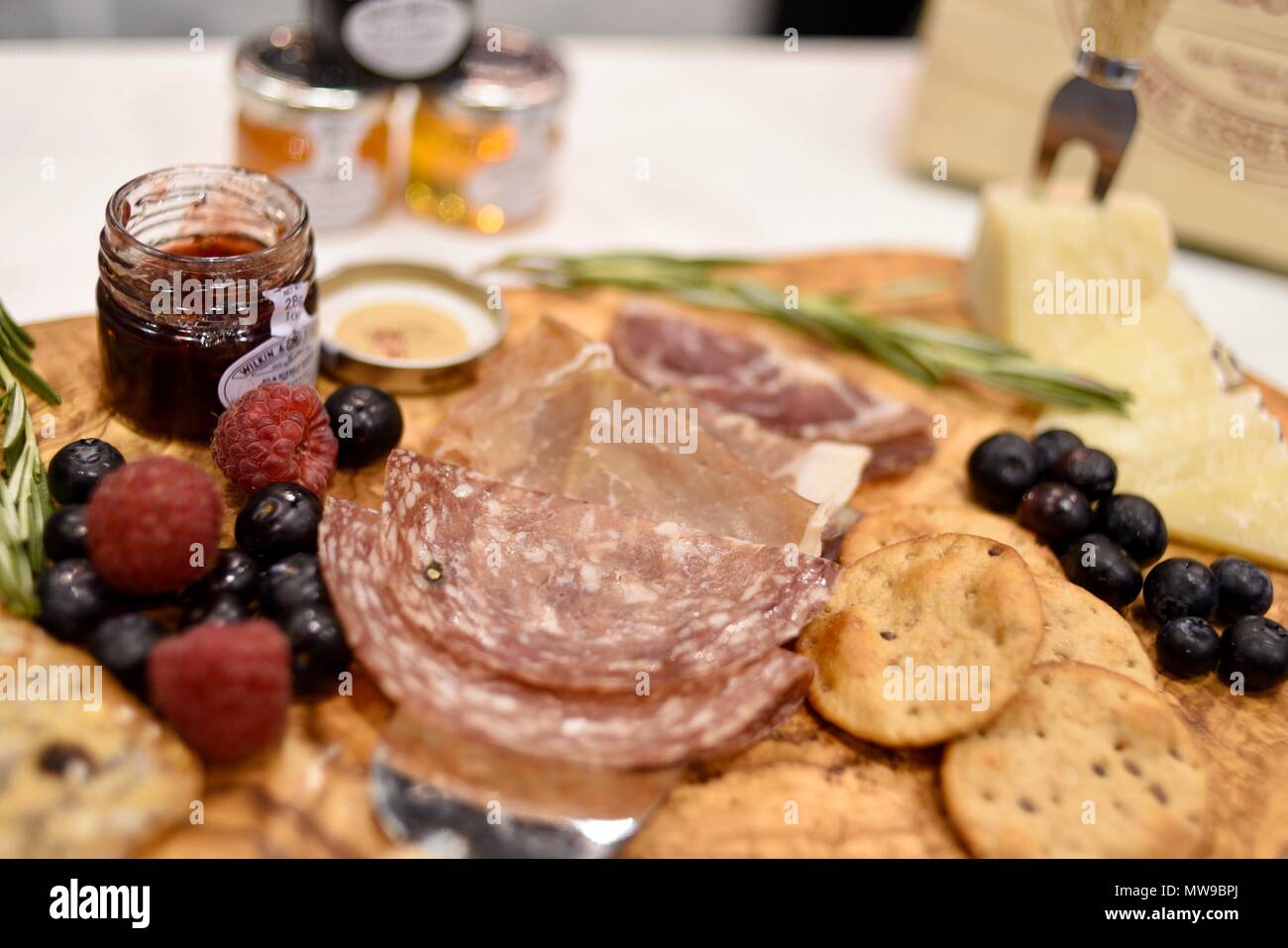 Charcuterie display del salame, formaggio, lamponi, uva, marmellate e cracker sul tagliere di legno. Foto Stock