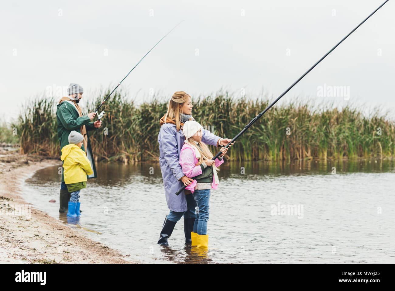 La famiglia felice in tute impermeabili e stivali pesca insieme Foto Stock