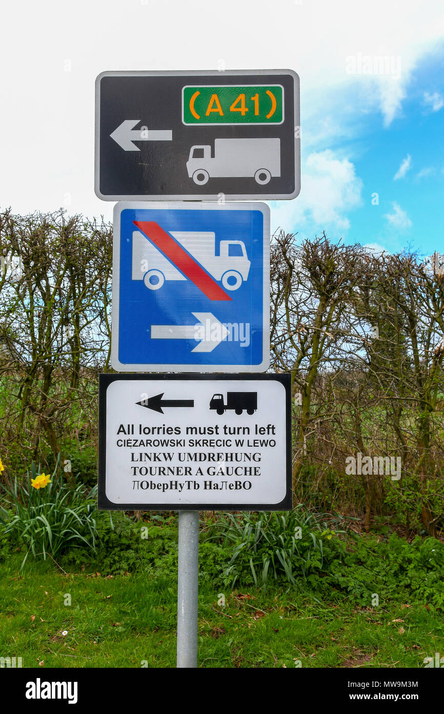 Un cartello stradale scritto in polacco, tedesco, francese e russo che raccontano gli autotrasportatori per girare a sinistra sulla A41 Foto Stock