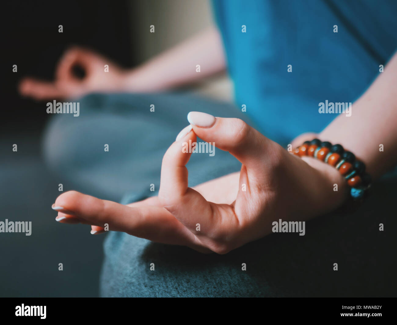 Primo piano della donna con le mani bracciali meditando in lotus pongono in ambienti chiusi. Gyan mudra. Lo Yoga, il concetto di religione. Foto Stock