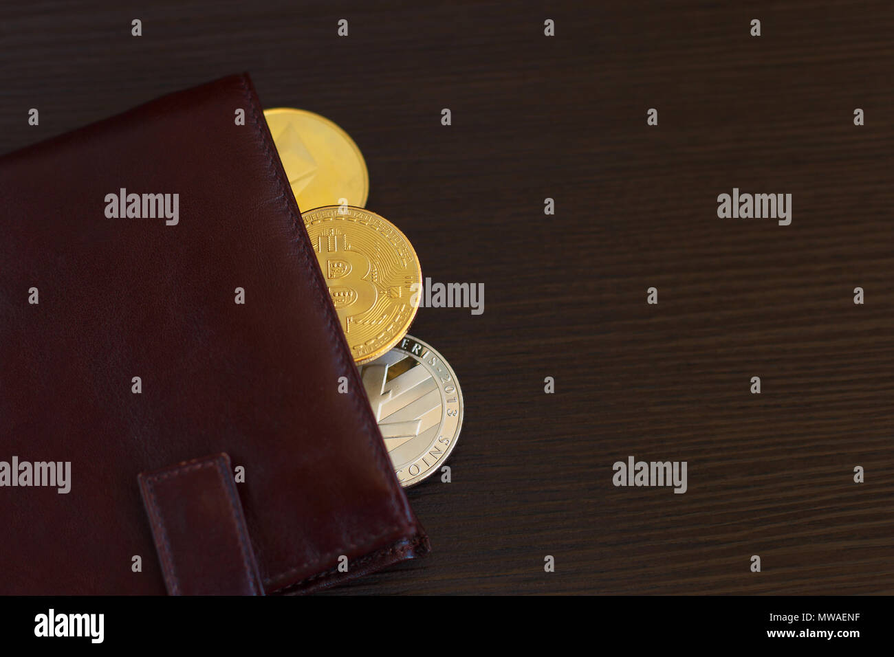 Crypto valuta moneta nel portafoglio in pelle su vasta in legno bitcoin sfondo ethereum litecoin. Foto Stock