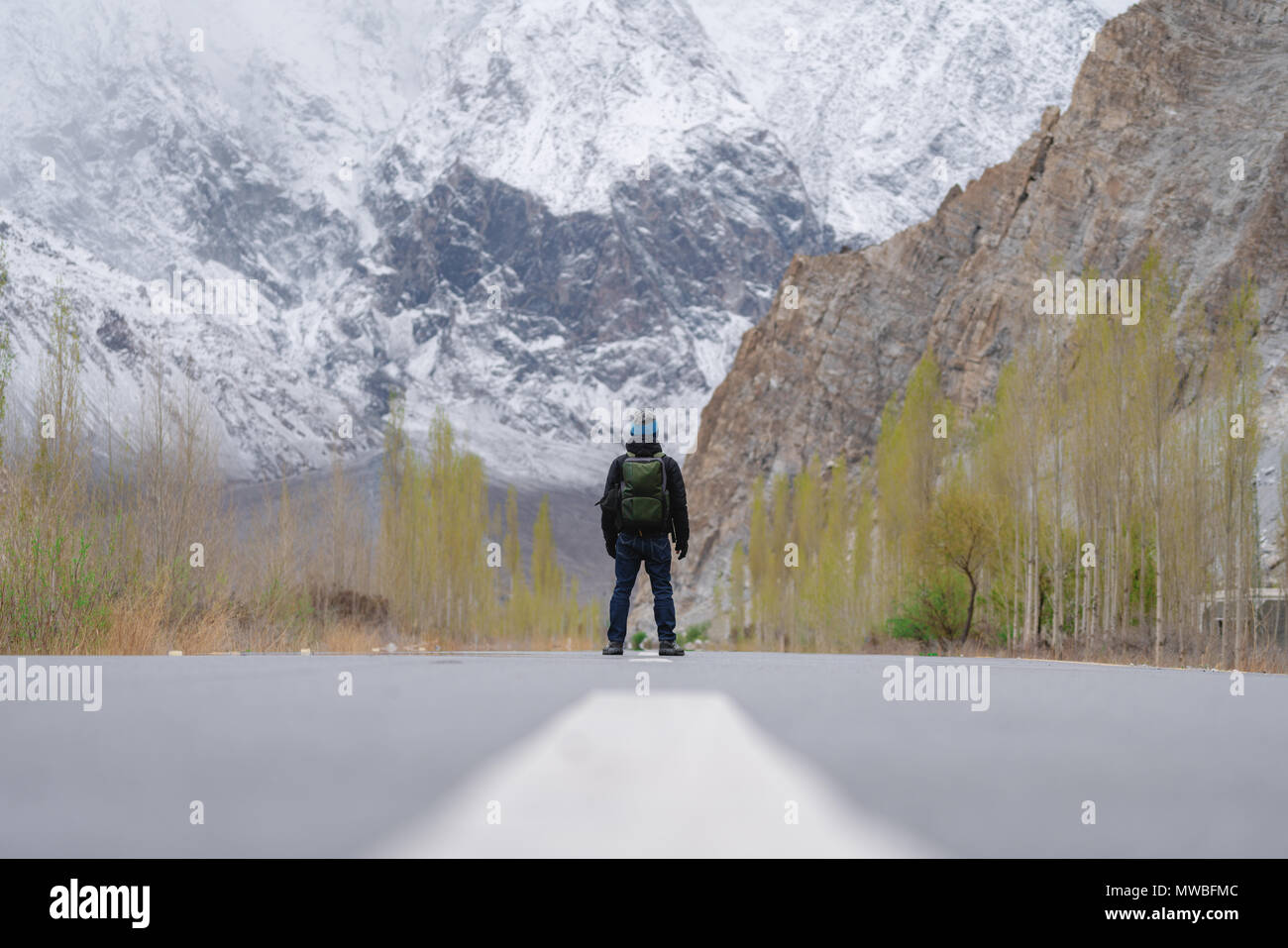 Un uomo con zaino in piedi da solo sulla strada vuota nel nord del Pakistan Foto Stock