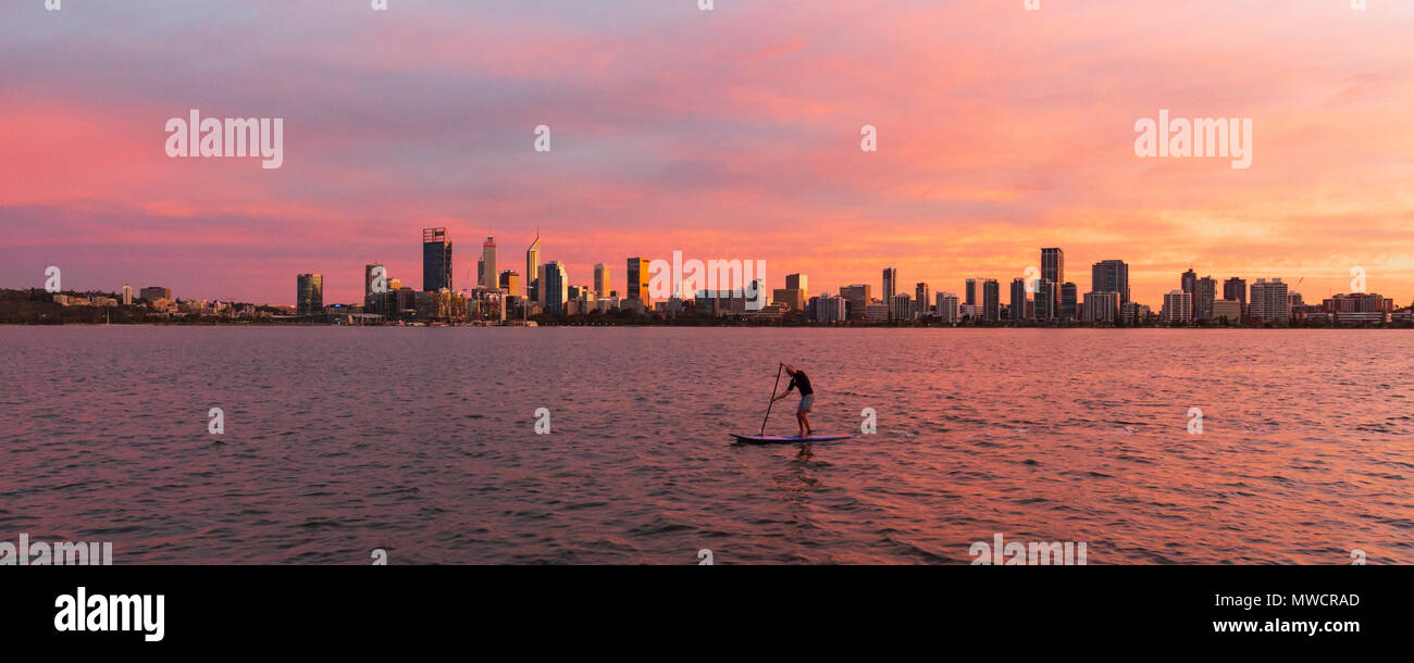 Un uomo alzarsi paddleoarding sul fiume Swan con la città di Perth in distanza. Australia occidentale Foto Stock