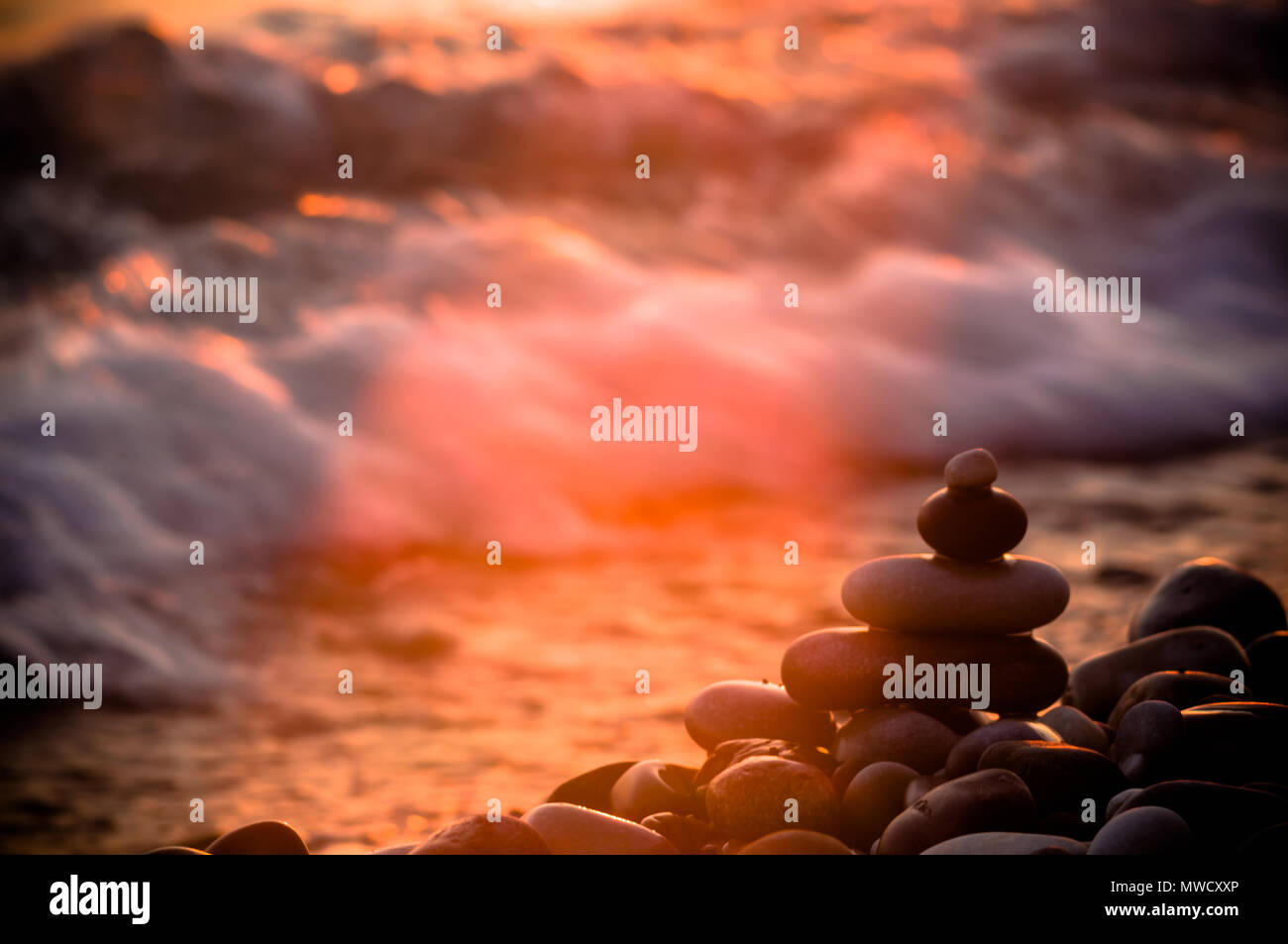 Piramide piegata Zen pietre ghiaia sul mare spiaggia al tramonto Foto Stock
