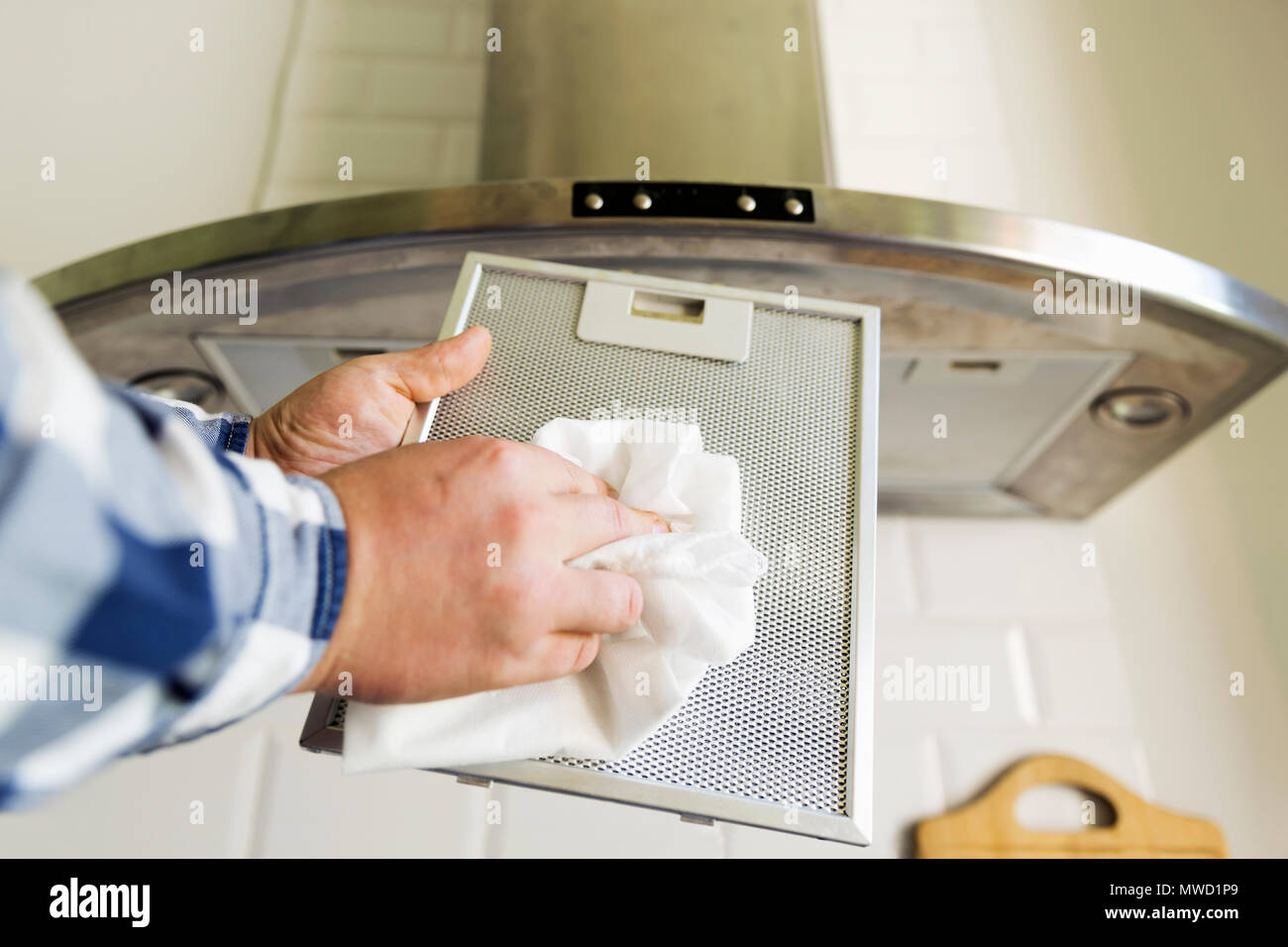 Uomo di pulizia delle mani in maglia di alluminio filtro per cappa. I lavori domestici e di faccende. Cucina cappa sullo sfondo Foto Stock