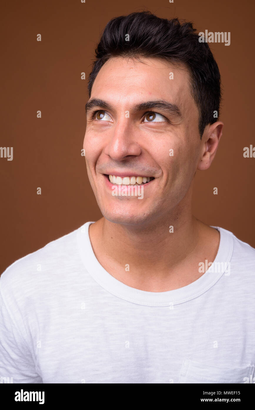 Bel giovane uomo ispanico contro sfondo marrone Foto Stock
