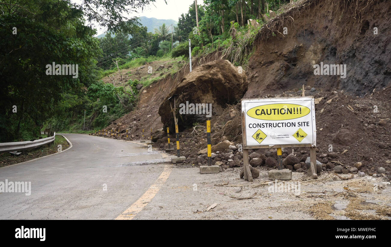 Smottamenti e frane sulla strada di montagna. Fango e rocce bloccando la strada.distrutto strada rurale frana danneggiato nel proiettore potente. Collassato su per la montagna. Filippine, Camiguin. Foto Stock