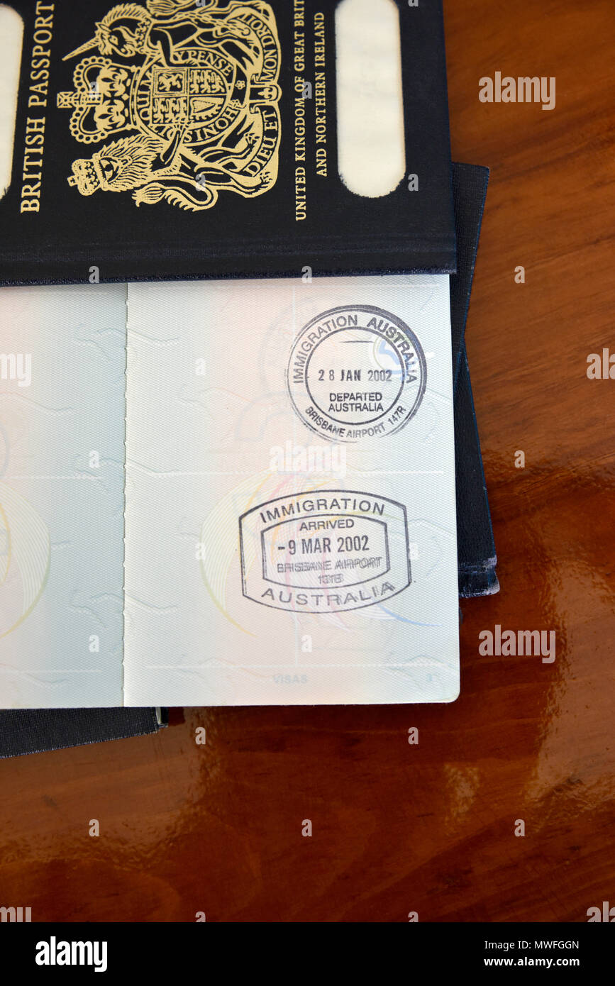 Brisbane arrivo e partenza francobolli in un passaporto australiano, in appoggio sul blu vecchi passaporti britannici Foto Stock