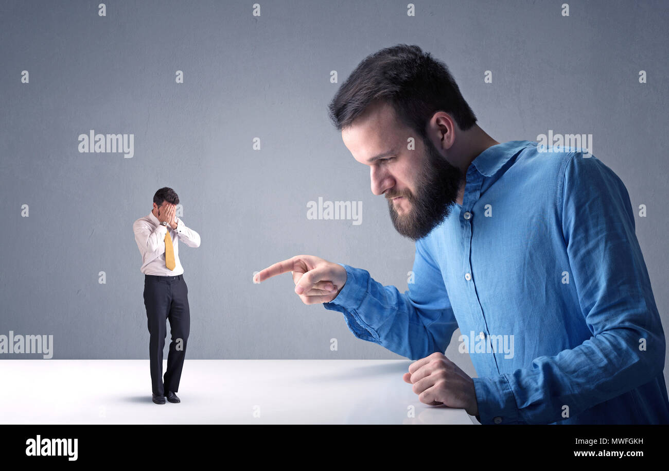 Giovane imprenditore professionale essendo arrabbiato con un altro imprenditore in miniatura Foto Stock