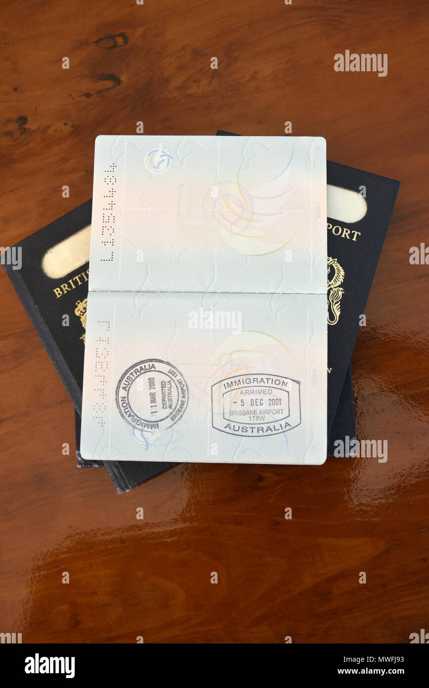Brisbane arrivo e partenza francobolli in un passaporto australiano, in appoggio sul blu vecchi passaporti britannici Foto Stock