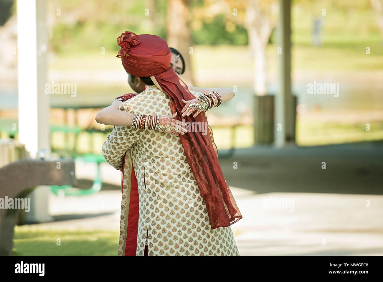 Indian lo sposo abbraccia la sposa nel parco Foto Stock