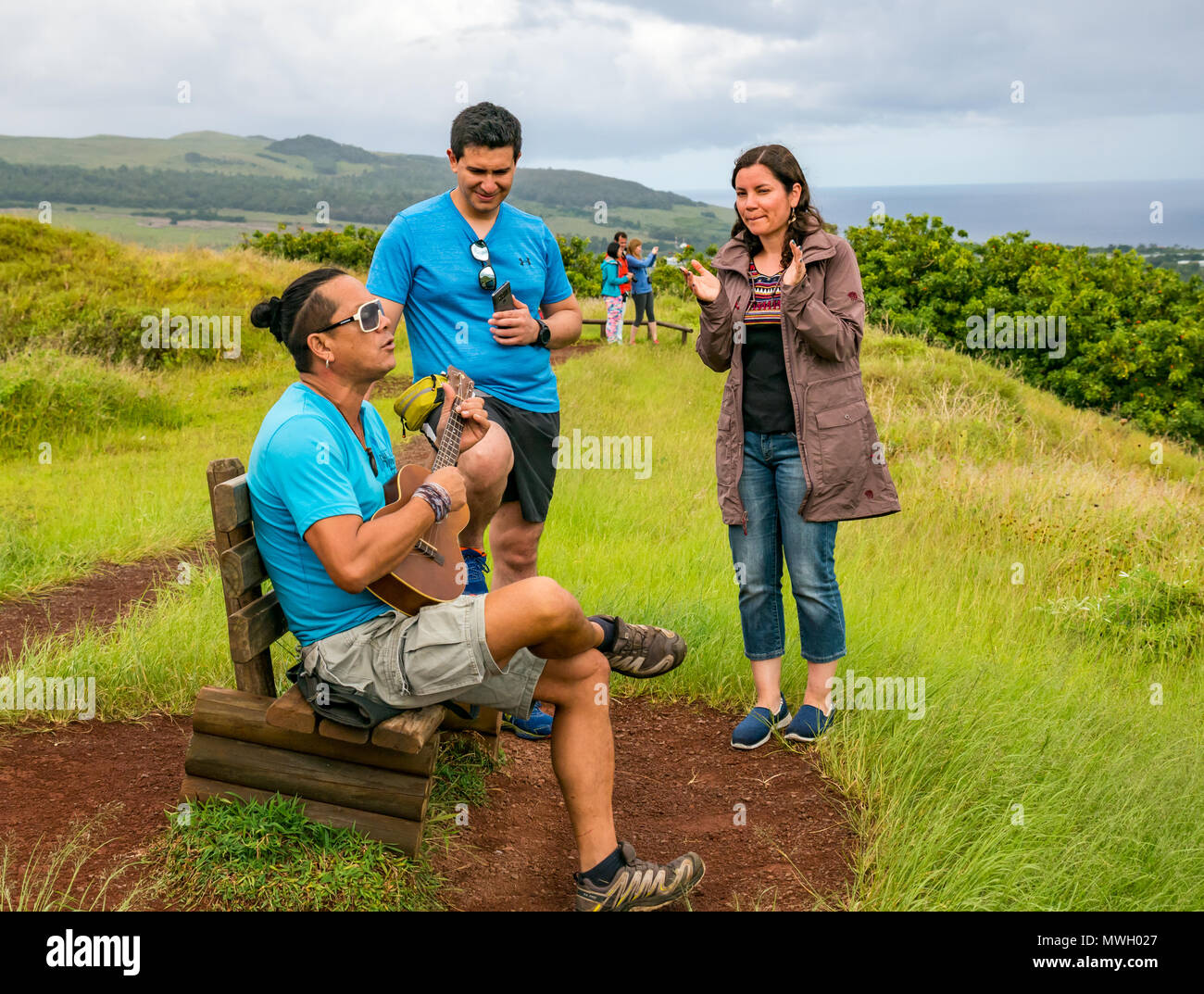 Chitarra improvvisato riproduzione di musica locale da uomo polinesiano con topknot, con coppia giovane pubblico e donna battimani, Puna Pau cava, Isola di Pasqua Foto Stock