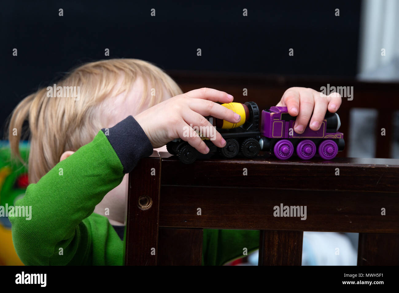 Giovani caucasici ragazzo Bimbi Gioca con i suoi treni giocattolo prima di andare a letto Foto Stock
