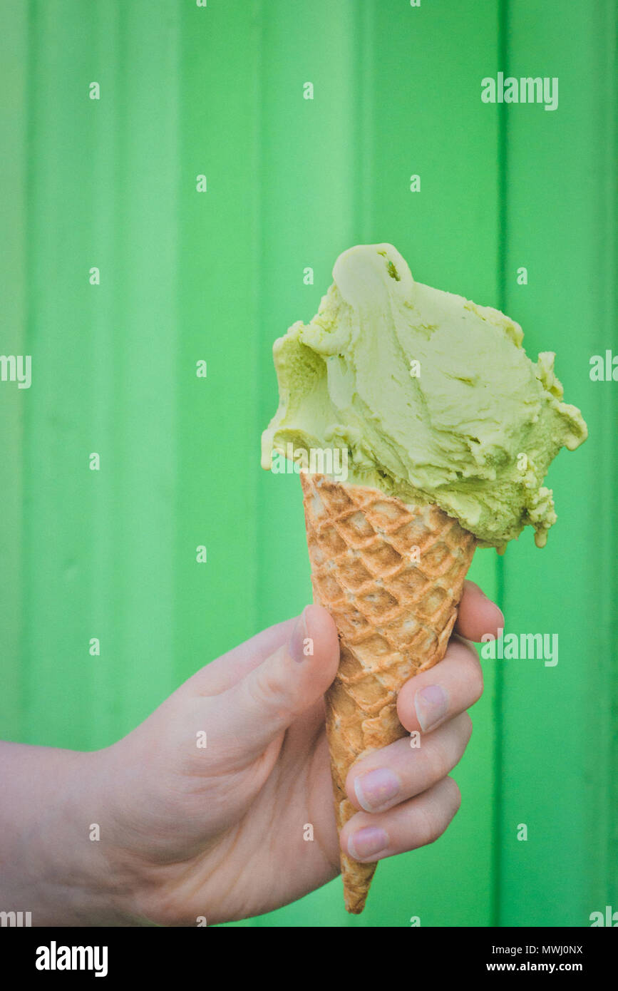 Cono di cialda con Matcha Ice Cream contro lo sfondo di colore verde Foto Stock