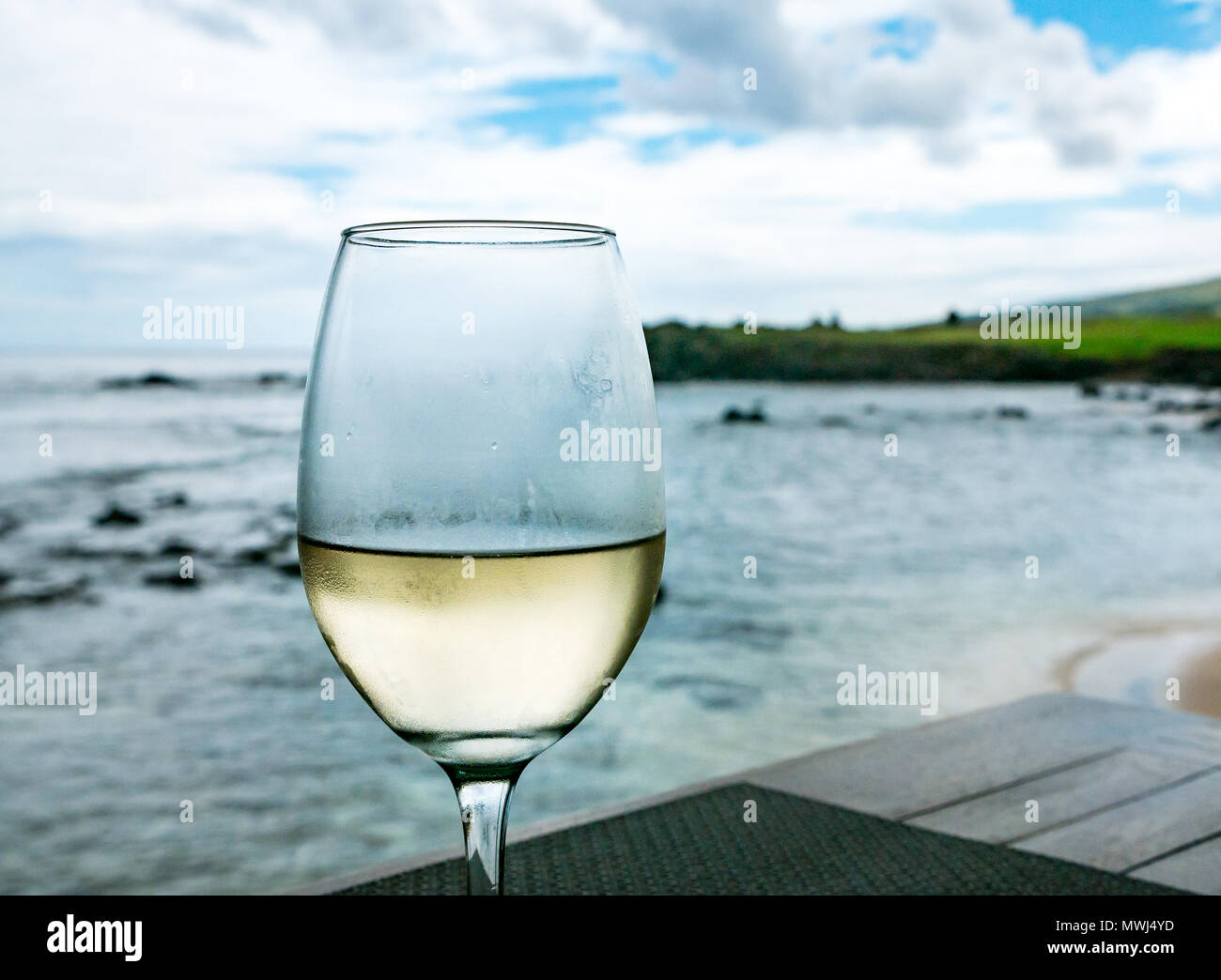 Chiusura del bicchiere di fresco vino bianco sul ponte del ristorante sulla spiaggia, Hanga Roa, Rapa Nui, Isola di Pasqua, Cile Foto Stock