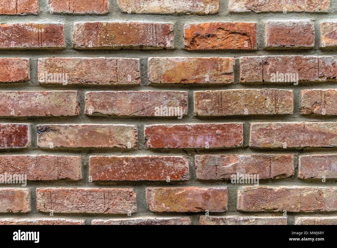 Un vecchio muro di mattoni restaurato con un fortemente sbiadito colore rosso e giunti irregolari, Germania Foto Stock