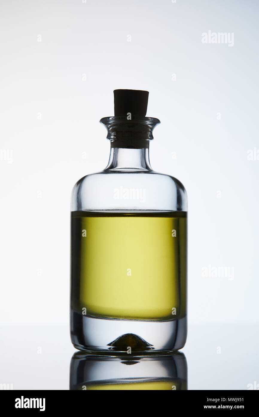 Flacone chiuso di olio aromatico di massaggio permanente sulla superficie riflettente Foto Stock
