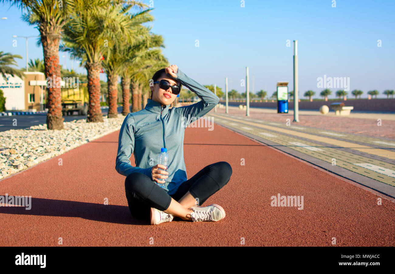 Ragazza seduta su una via di corsa e prendendo una pausa da allenamento Foto Stock