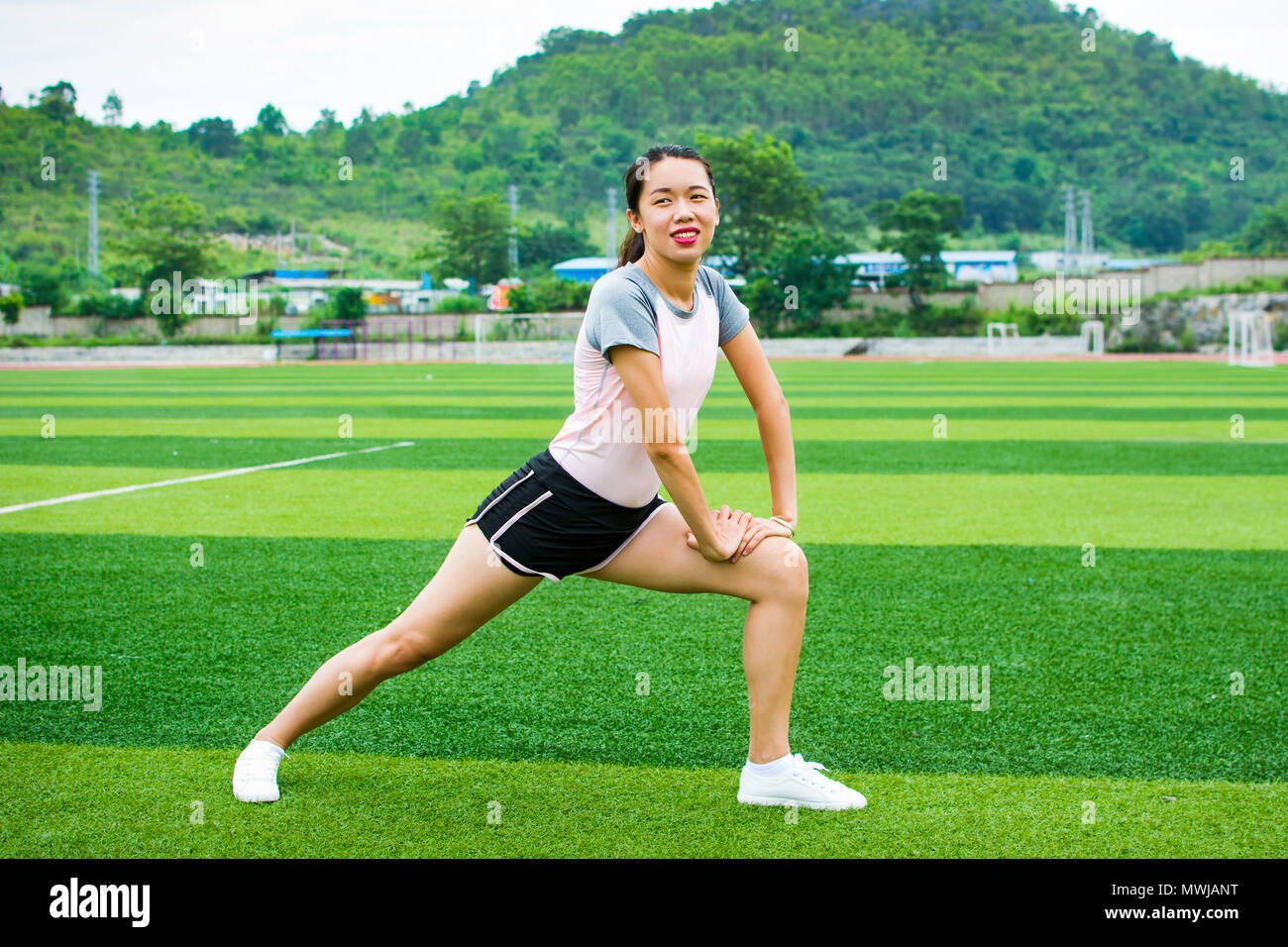 Ragazza stretching nel campo di calcio prima di fare jogging Foto Stock