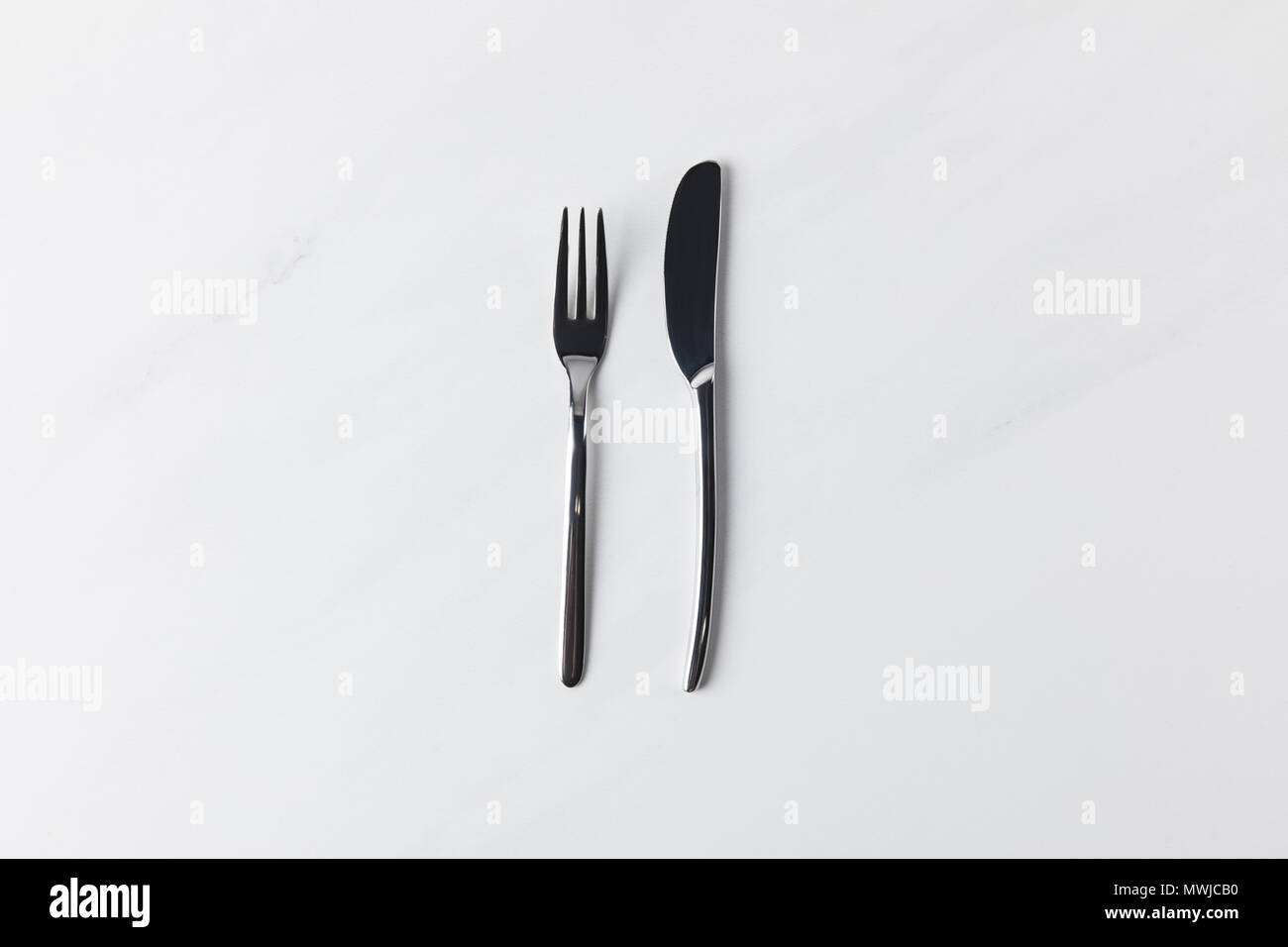 Coltello e forchetta collocata sulla superficie bianca, tabella concezione appuntamenti Foto Stock