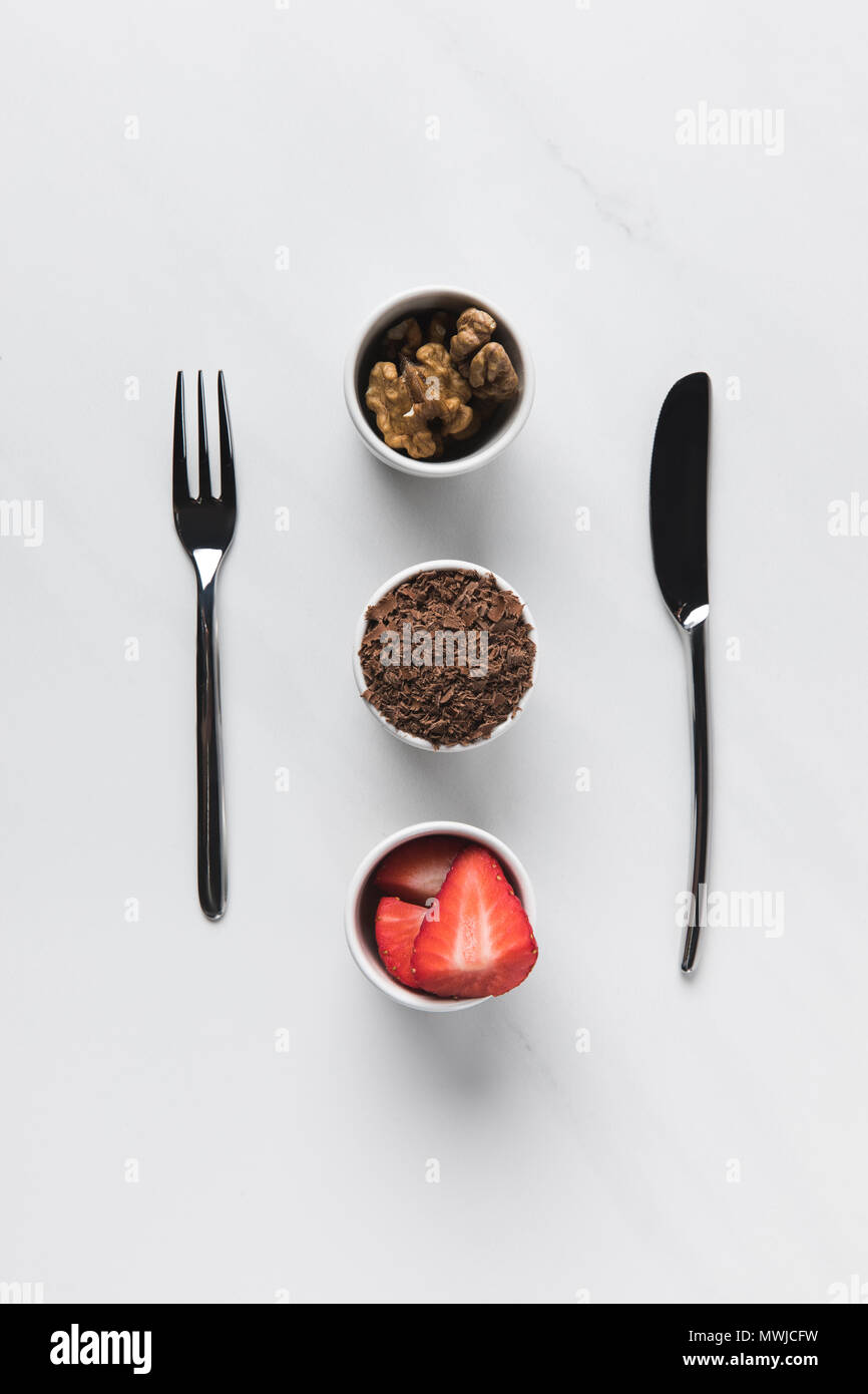 Bocce con noci, cioccolato grattugiato e fragole tra coltello e forchetta, tabella appuntamenti concepimento Foto Stock
