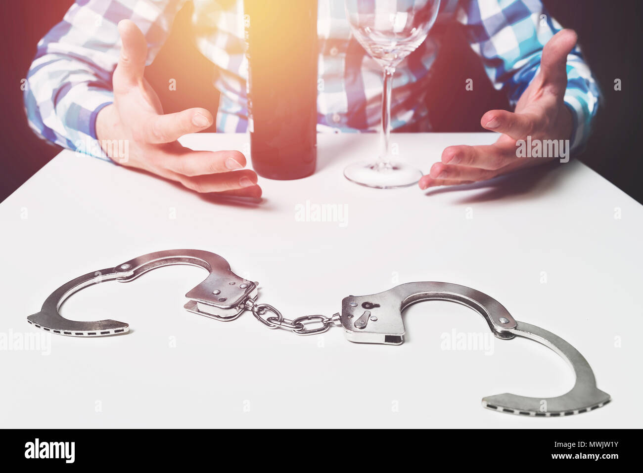 La dipendenza da alcol, liberando te stesso da alcool, problemi con la vodka, il vino. Ci sono le manette sul tavolo, sullo sfondo di un uomo con bracci sp Foto Stock