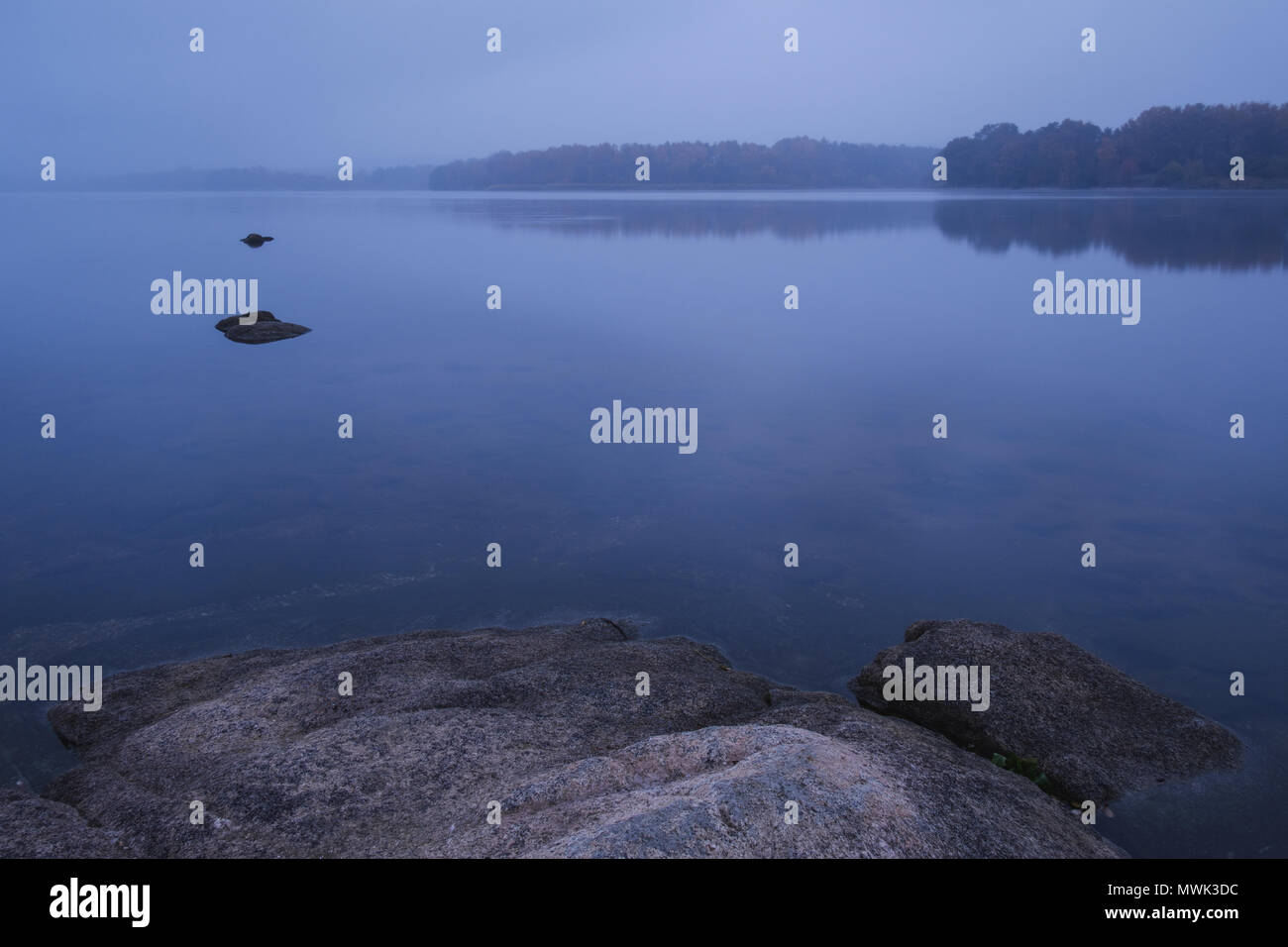 Blu scuro mattinata nebbiosa sul lago Foto Stock