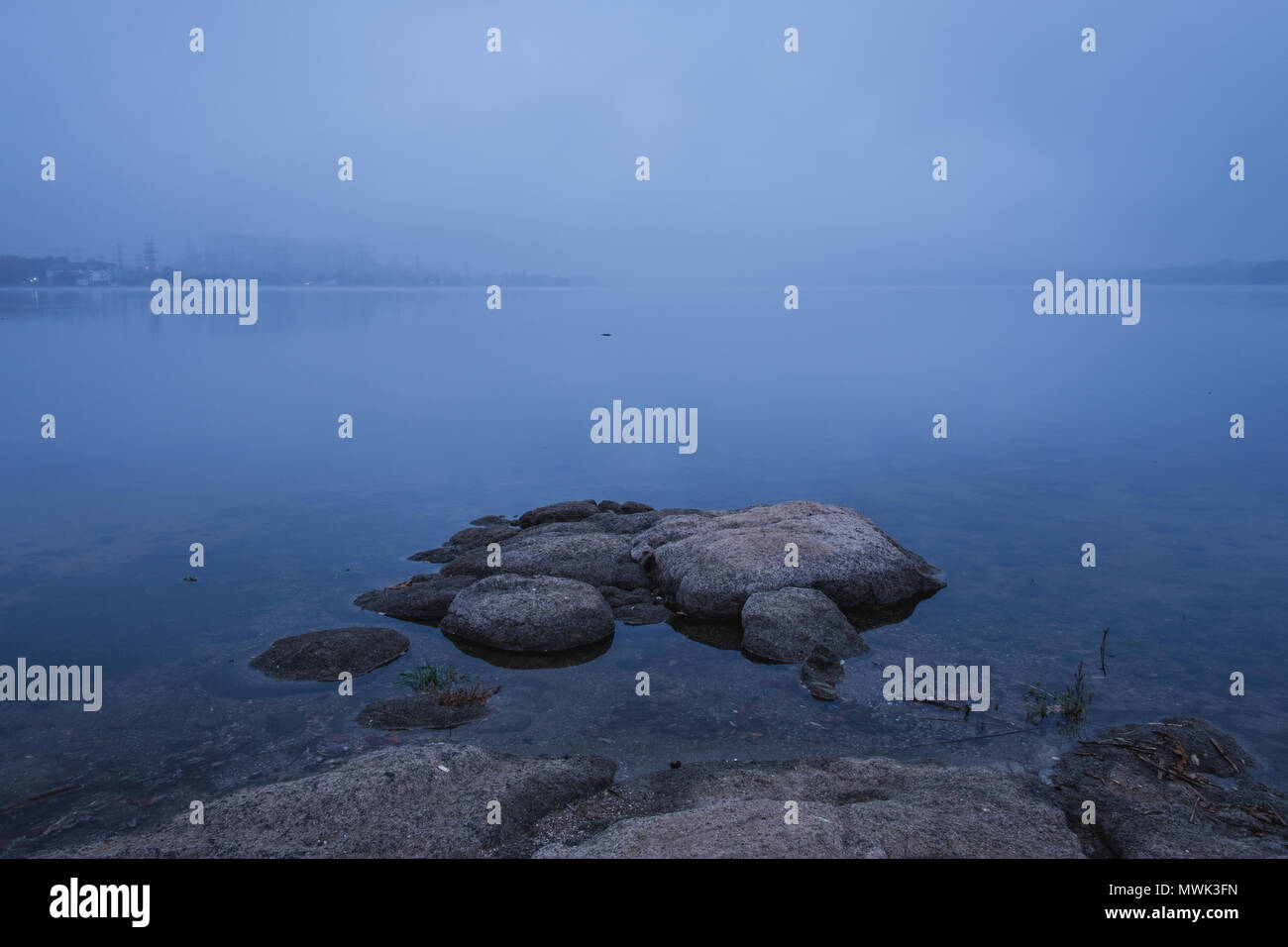 Blu scuro mattinata nebbiosa sul lago Foto Stock